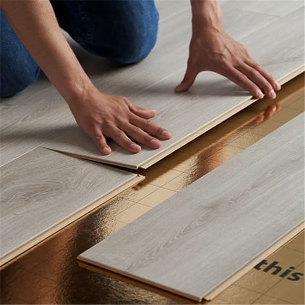 man installing a beige click laminate floor on an underlay